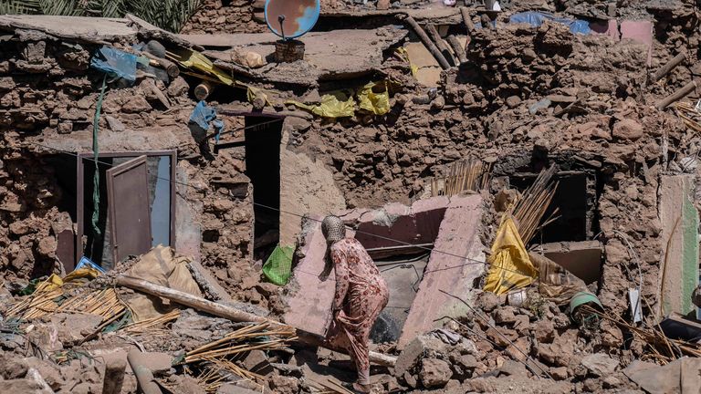 A woman tries to recover some of her possessions from her home which was damaged by the earthquake in the village of Tafeghaghte, near Marrakech, Morocco, Monday, Sept. 11, 2023. Rescue crews expanded their efforts on Monday as the earthquake's death toll continued to climb to more than 2,400 and displaced people worried about where to find shelter. (AP Photo/Mosa'ab Elshamy)