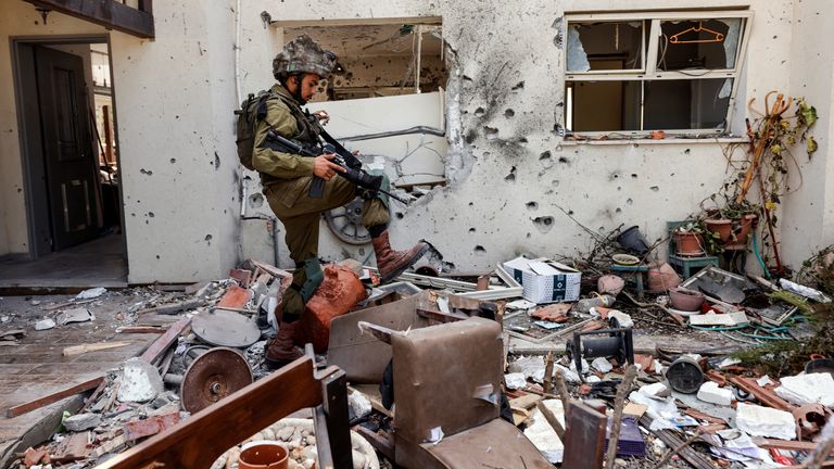 An Israeli soldier steps over personal belongings near a home, following a mass infiltration by Hamas gunmen from the Gaza Strip, in Kibbutz Beeri in southern Israel, October 13, 2023. REUTERS/Amir Cohen